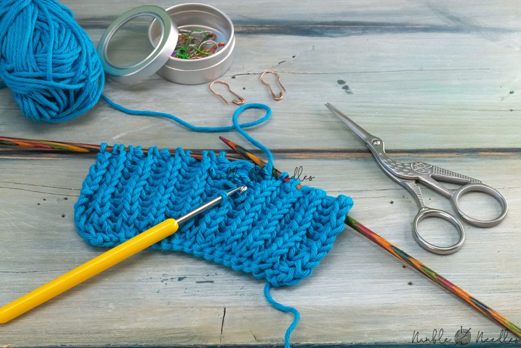 fixing mistake in brioche knitting using cotton yarn and a crochet hook on a table