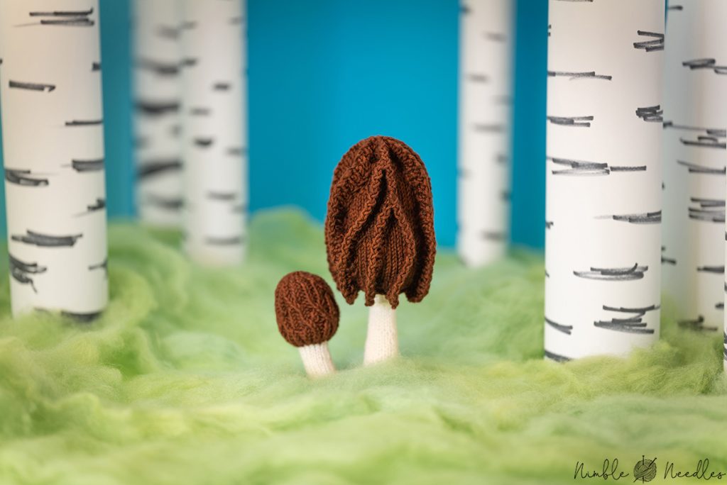 two knitted morels in a fake birchwood forest