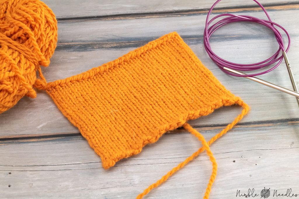knitted swatch in orange yarn on a table