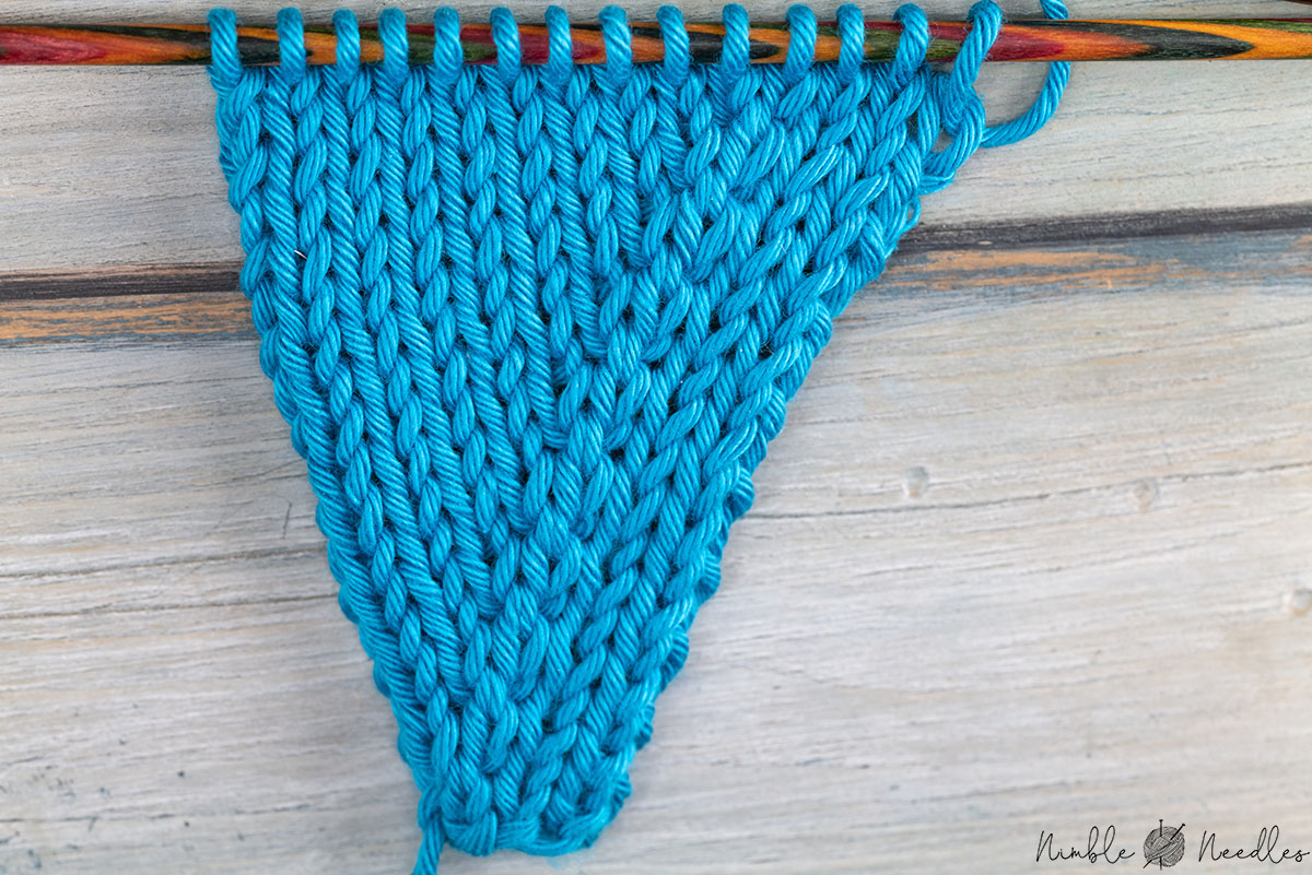 a knitted swatch in blue yarn increased with the hitch knot increase
