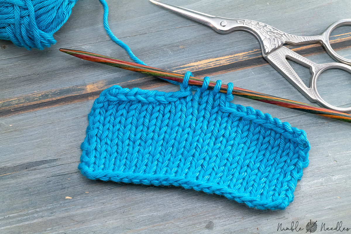 a swatch bind off both sides with knitting tools and yarn in the background