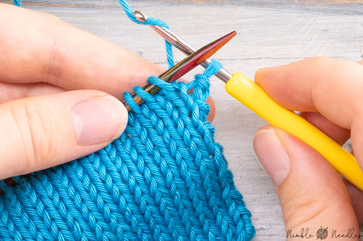 grabbing the working yarn and pulling it through the last edge stitch