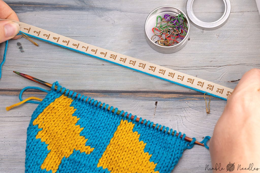 measuring the distance between two stitch markers with a tape measure