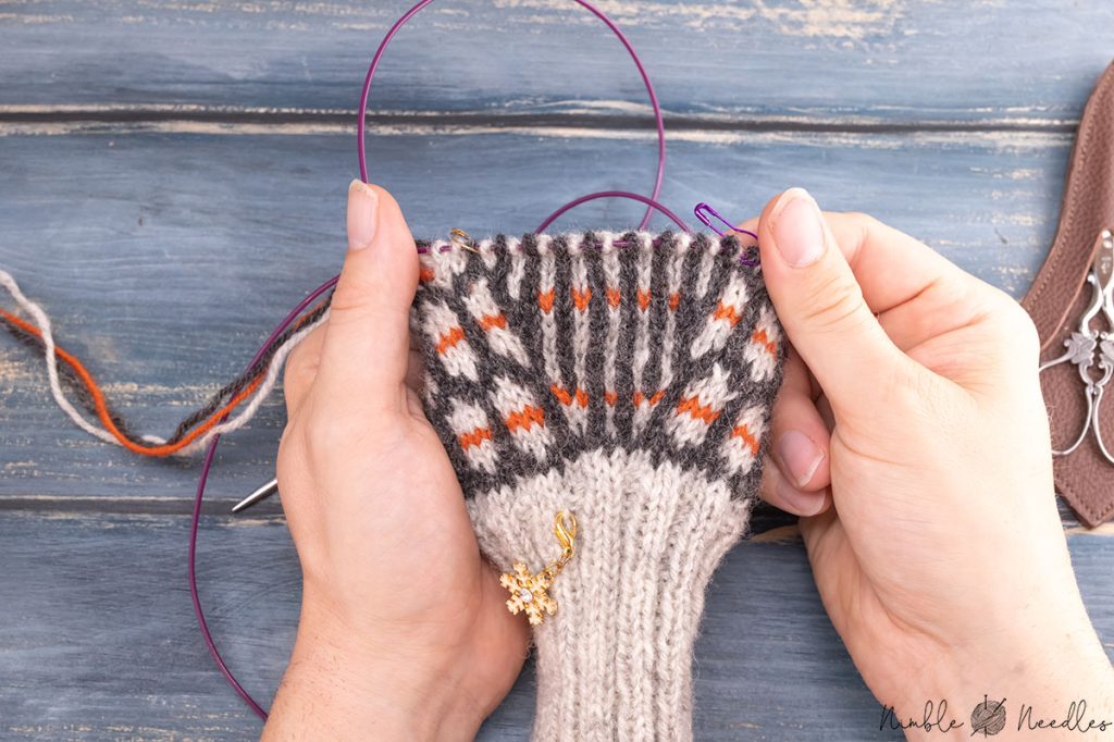 someone holding a pair of unfinished mittens with the gusset spread out
