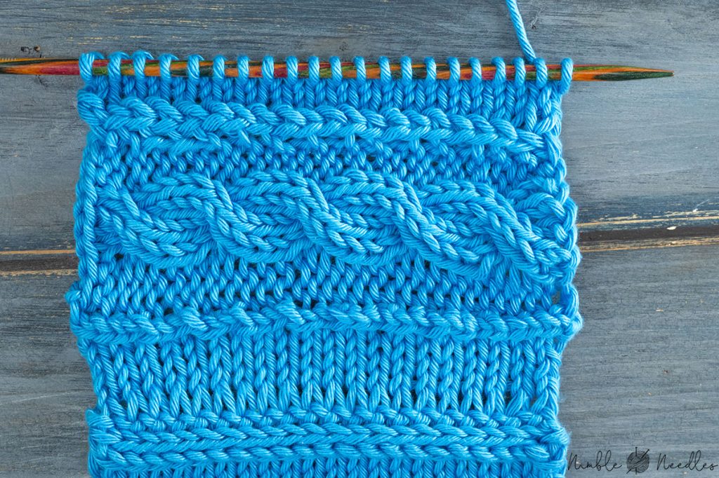 A swatch with a horizontal 2x2 cable stitch knitted in blue yarn