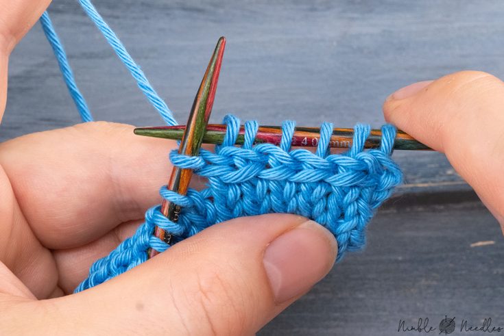 someone showing how to knit horizontal cables with blue yarn